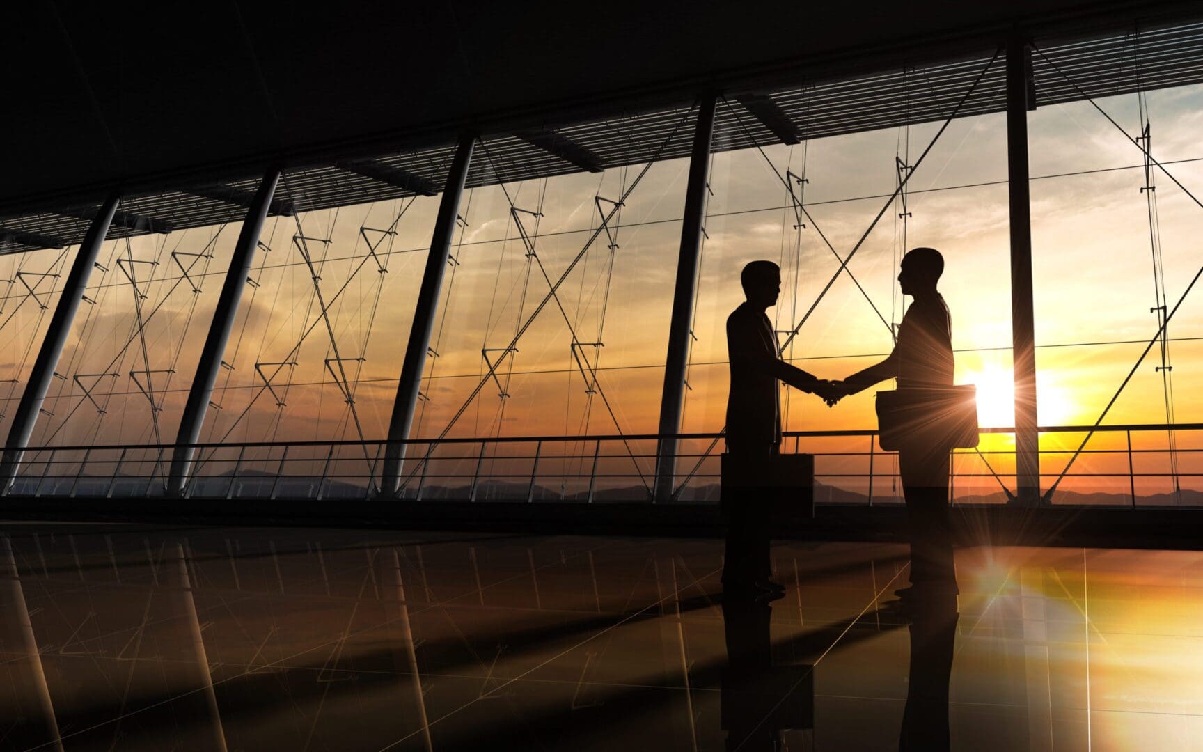 Two business people shaking hands during sunset in an office.