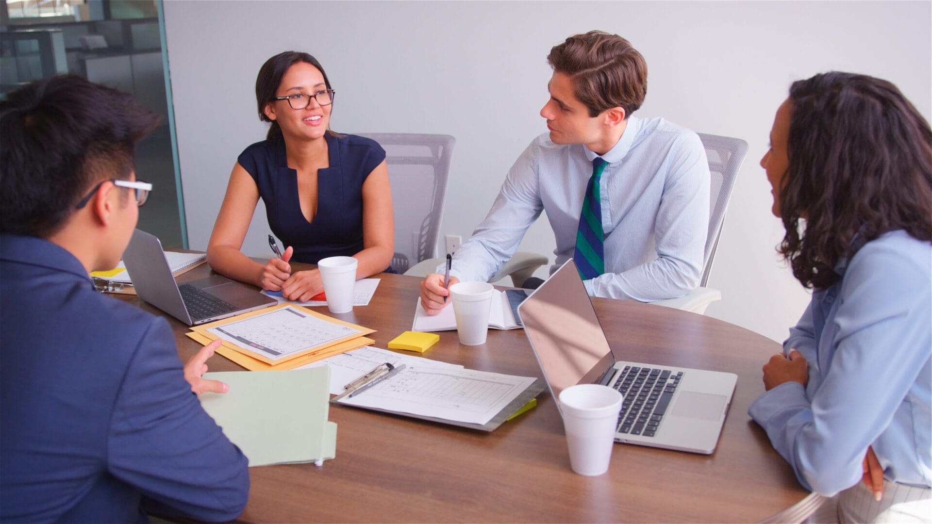 Two colleagues engaged in a discussion at a modern office desk.
