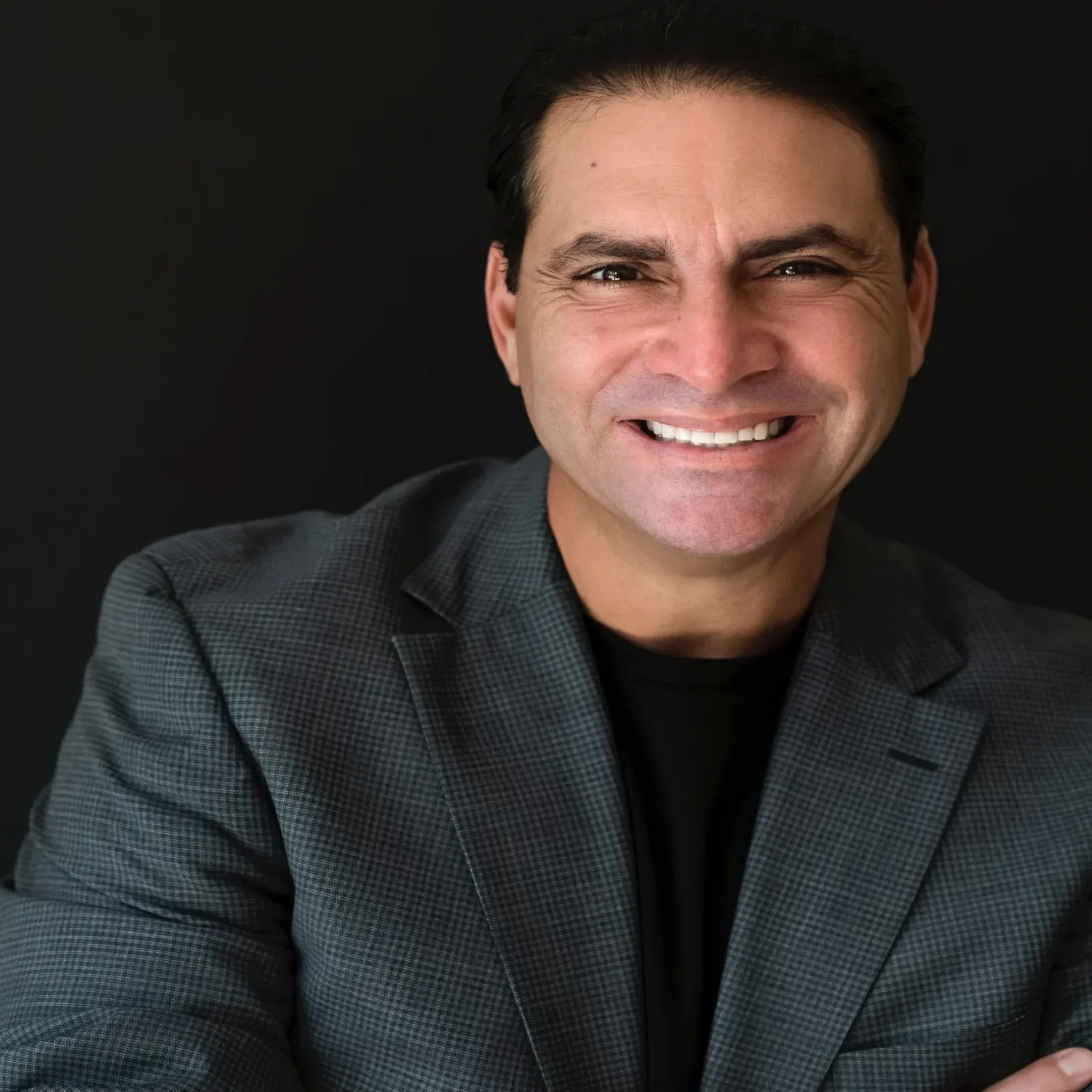 Smiling man in gray blazer, arms crossed