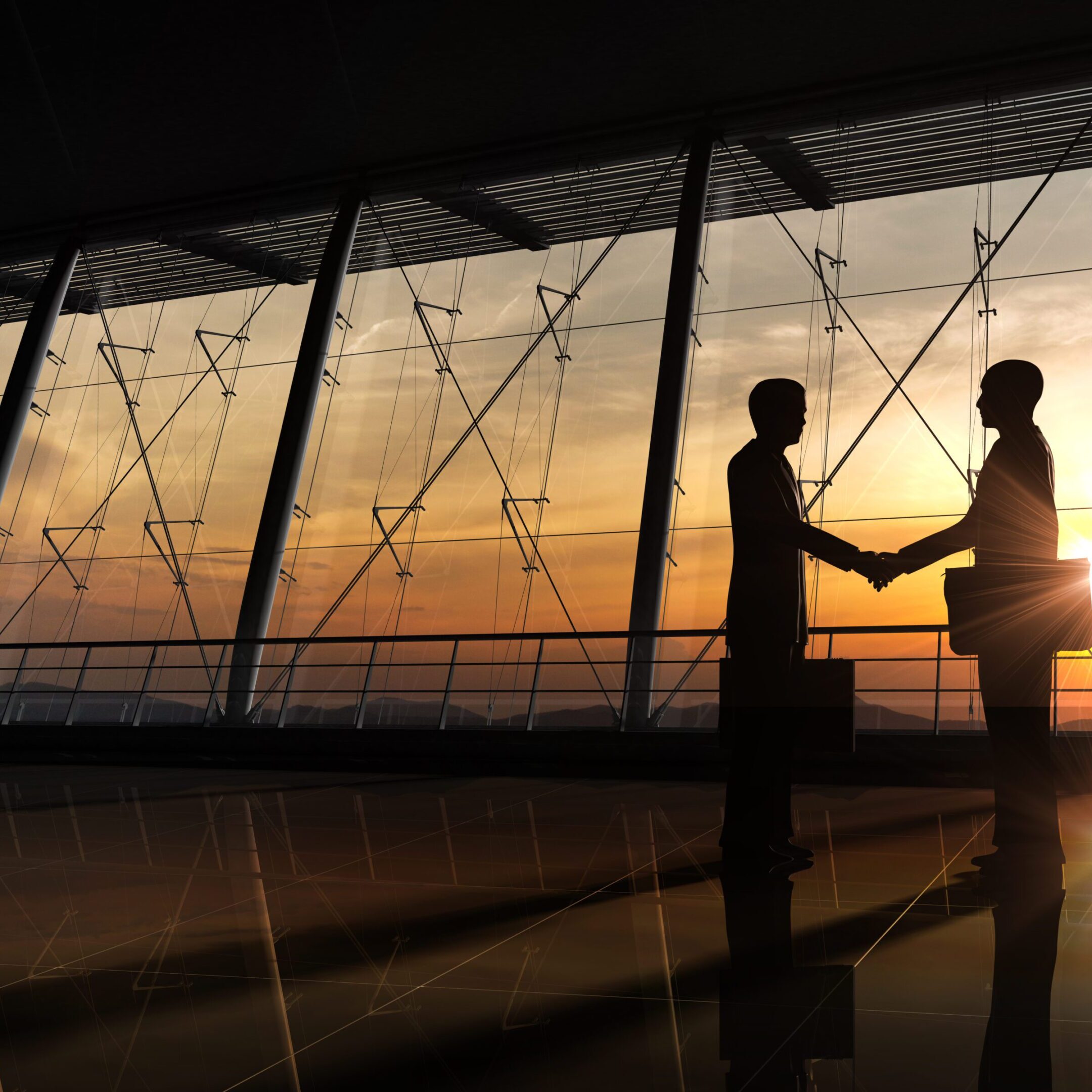 Two business people shaking hands during sunset in an office.