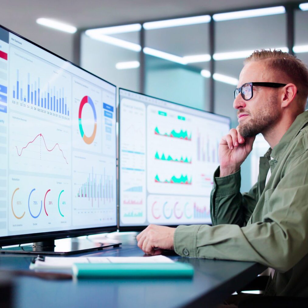 Man analyzing data on computer screens.